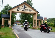 2 motorcycles riding under an archway with sign Best Northern Resort