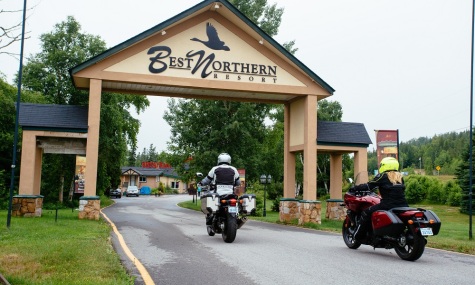 2 motorcycles riding under an archway with sign Best Northern Resort