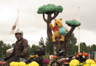 motorcycle rider with motorcycles standing in front of winnie the pooh and tree statue