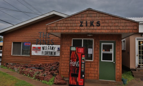 a ceder sided building with signs that read the Pines and Ziks